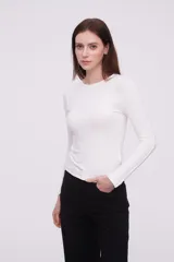 Remera ajustada color marfil, de manga larga y diseño minimalista.