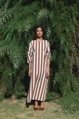 Vestido largo con estampado a rayas verticales color marrón y blanco, de corte recto y mangas largas con puños elásticos.