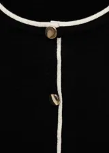 Cárdigan negro de punto fino con cuello redondo y cierre frontal con botones blancos.