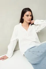 Blusa color amarillo pálido de manga larga con escote en V, mangas abullonadas con volados y botones forrados.