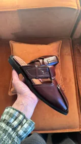 Sandalia de cuero negro con diseño abierto y correa con hebilla.