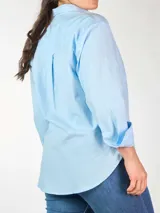Camisa celeste de calce holgado, manga larga con puño ancho y doble botón, doble bolsillo plastrón en delantero y tajos laterales.