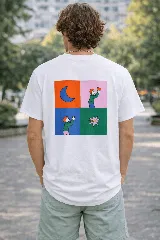 Remera blanca de algodón premium con estampado gráfico en la espalda dividido en cuatro cuadros: una luna creciente azul sobre fondo naranja, una figura humana sosteniendo un objeto rojo sobre fondo rosa, una figura humana sosteniendo un objeto blanco sobre fondo azul, y una flor estilizada rosa sobre fondo verde oscuro.