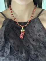 Collar corto con cuentas de coral rojo y detalles de bronce. Incluye un dije con forma de cuerno de la abundancia.