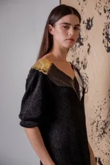 Vestido negro de noche con mangas 3/4, cuello en V con detalles de cuero entrelazado, terminación en flecos y tajos laterales.