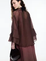 Camisa negra de lyocell y poliamida, con cuello clásico, mangas largas acampanadas con volados y cierre frontal con botones.