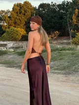 Top de crochet en hilo marrón con acabado brilloso. Diseñado con espalda libre y tiras ajustables que se atan atrás, este top realza la figura y suma un toque bohemio y sofisticado a cualquier look.