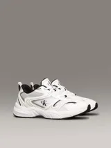 Zapatillas urbanas Calvin Klein Jeans, de estilo retro, color blanco con detalles en plateado y negro. Confeccionadas en malla y cuero sintético, con logo CK en el lateral.