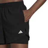 Short deportivo negro de mujer, con calza interior ajustada y capa exterior holgada con aberturas laterales. Logo de Adidas estampado en blanco en la pierna izquierda.