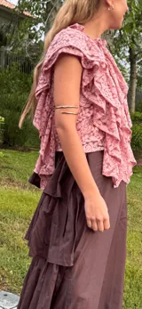 Blusa rosa de encaje con volados y cuello alto.
