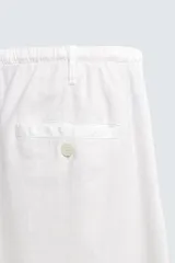 Pantalón negro de corte relajado y pierna ancha, confeccionado en mezcla de algodón y lino. Presenta cintura elástica ajustable con cordón y cierre frontal con cremallera y botón.