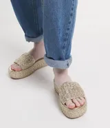 Sandalia flatform negra con superficie trenzada, tira ancha y puntera redonda.