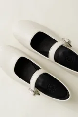 Zapato estilo Mary Jane color marrón, de cuero, con punta redondeada y tira sobre el empeine con hebilla.