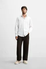 Camisa de vestir slim fit de algodón, color blanco con diseño de cuadros en tonos grises y beige. Tiene cuello italiano, mangas largas con puños abotonados y cierre frontal con botones.