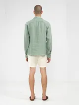 Camisa celeste de lino, de manga larga con botones de coco y parche de la marca.