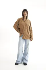 Camisa de pana color borgoña, de corte oversize, con cuello clásico, cierre frontal con botones, dos bolsillos con solapa en el pecho y mangas largas con puños abotonados.