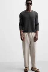 Pantalón de lino color marrón oscuro, de corte recto y relaxed fit. Tiene cintura elástica ajustable con cordón, bolsillos frontales y traseros de parche.