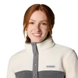 Buzo polar Columbia Benton Springs para mujer, de corte clásico, con cuello alto y cierre parcial con botones a presión. Diseño en bloques de color: blanco en la parte superior y gris en la inferior.