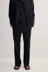 Pantalón negro de corte recto, confeccionado en mezcla de lino y algodón. Presenta cintura elástica con cordón ajustable, bolsillos laterales y bolsillo trasero insertado.