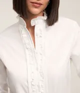 Camisa blanca de tricolina con cuello padre, abotonada al frente con detalle ondulado y mangas largas.