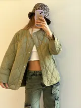 Campera verde militar con diseño capitoneado, cuello redondo y cierre frontal con botones a presión.