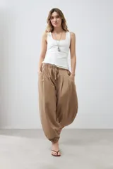 Pantalón tipo barrel color tostado, confeccionado en lino, con cintura elástica y cordón ajustable.