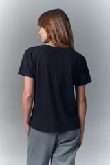 Remera negra de algodón con cuello redondo y mangas cortas. Presenta un estampado en el escote que simula un collar estilo boho con cuentas, borlas y dijes.