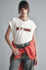 Remera blanca de algodón con mangas cortas, calce relajado y escote redondo. Presenta un bordado frontal con canutillos formando la frase "Je t'aime".