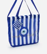 Bolso tipo tote plegable con estampado de rayas verticales azules y blancas. Incluye asas dobles azules, estampado de ojo turco y texto 'make a wish' en dorado. Incluye un pequeño estuche con cierre y estampado a rayas.