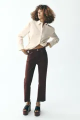Jeans de tiro alto color marrón, corte slim fit y bootcut, con cinco bolsillos y cierre frontal con cremallera y botón.
