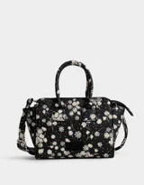 Cartera mini city de cuerina negra estampada con flores blancas. Tiene correa desmontable y doble asa corta.