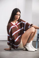 Remera de algodón y poliéster a rayas horizontales rojas y azul marino sobre fondo crudo. Tiene cuello tipo polo con botones, mangas amplias y corte oversized.