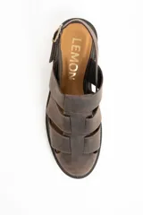 Sandalia tipo cangrejera de cuero marrón oscuro, con puntera cerrada tejida con tiras anchas y talón descubierto con tira ajustable y hebilla metálica. Posee suela de goma oscura y plantilla de cuero color camel con la marca grabada.