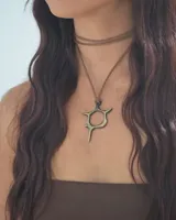 Gargantilla doble de cuero sintético color marrón, con dije metálico dorado de forma abstracta.