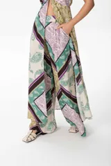 Pantalón sastrero de corte oversize con estampado paisley en tonos verde, lila, marrón y beige. Pretina ancha en la parte delantera y elástico en la parte trasera.