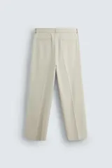 Pantalón de vestir color beige, corte wide fit, con cintura elástica, pliegues frontales, bolsillos laterales y traseros de vivo.