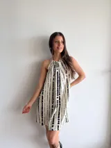 Minivestido blanco con estampado de líneas verticales negras, cuello halter con ajuste elástico y corte suelto.