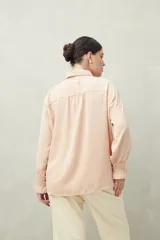 Camisa negra de manga larga con cuello clásico y botones frontales. El tejido presenta una textura arrugada o plisada, y los puños tienen un detalle fruncido o elástico.