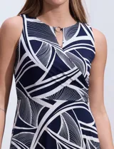Vestido largo de seda fría con estampado abstracto en blanco y azul marino. Tiene cuello a la base cruzado con abertura ojal y aplique metálico.