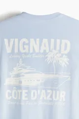 Remera celeste de algodón con cuello redondo y estampado frontal con la palabra "VIGNAUD" y un dibujo de una lancha.