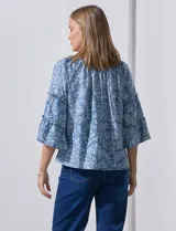 Blusa celeste de lyocell con estampado floral blanco, cuello redondo con frunce y mangas 3/4 con volados.