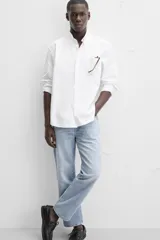 Camisa azul marino de corte regular fit, confeccionada en tejido de algodón Oxford. Tiene cuello abotonado, manga larga con puños abotonados, bolsillo de parche en el pecho y cierre frontal con botones.