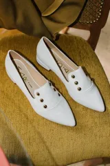 Chatitas negras de cuero con punta fina y apliques de tachas doradas.