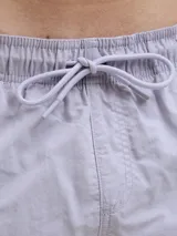 Short de baño lila con cintura elástica ajustable con cordón. Estampado lateral con el logo de la marca y texto en blanco.