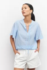 Blusa celeste a rayas verticales con cuello mao, mangas cortas y lazo en el frente.
