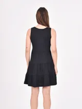 Vestido corto color coral, de corte suelto y sin mangas, con escote en V y falda escalonada con volantes.