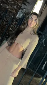 Polera corta color beige, de hilo con cuello alto y mangas largas acampanadas.