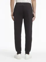 Pantalón de jogging negro con cintura elástica, bolsillos laterales y logo de Calvin Klein estampado en blanco en la pierna derecha.
