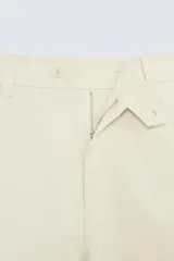 Pantalón chino color beige, corte recto, con bolsillos laterales y traseros. Cierre frontal con cremallera y botón.