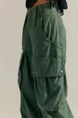 Pantalón cargo de inspiración utilitaria, color verde militar, con calce holgado en toda la pierna y tiro medio. Presenta grandes bolsillos utilitarios con tapa y detalles de costuras visibles.